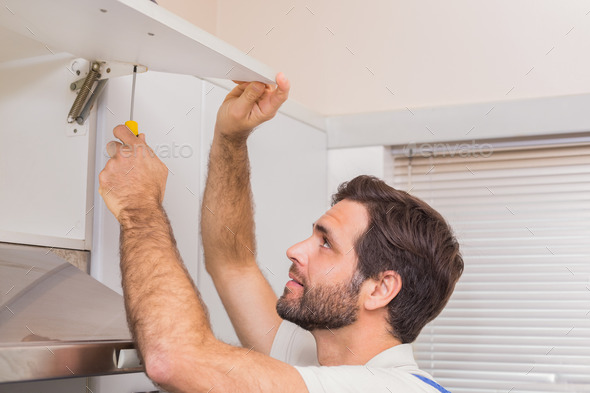 Handyman putting up a shelf in the kitchen (Misc) Photo Download