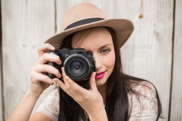 Pretty brunette taking a photo against bleached wooden planks (Misc) Photo Download
