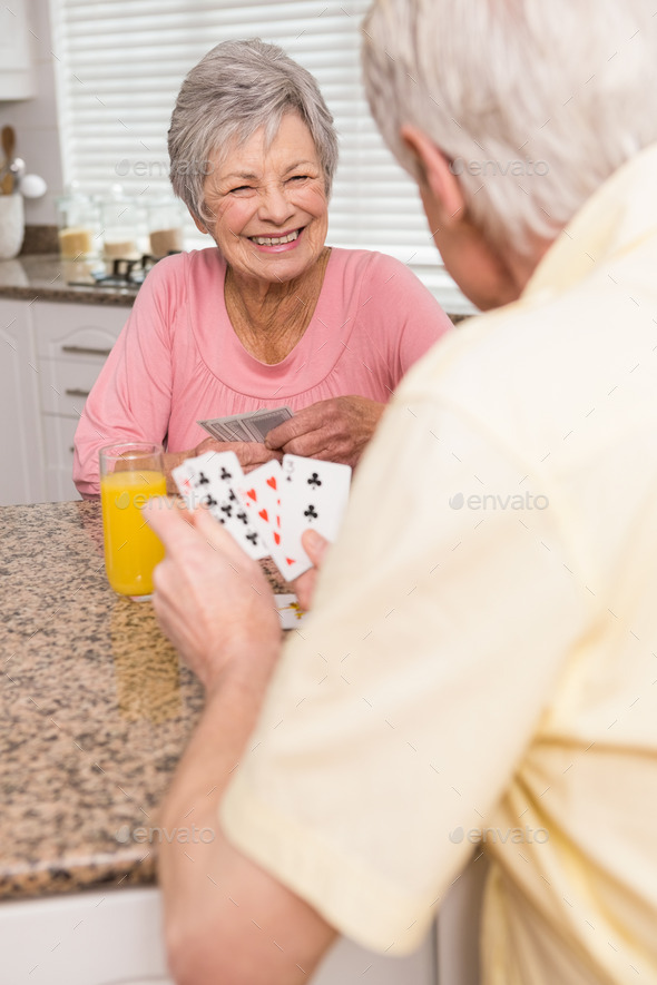 Senior couple playing cards at the counter at home in the kitchen (Misc) Photo Download