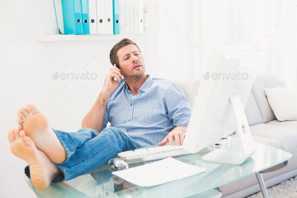 Businessman on the phone using his computer with his feet up in his office (Misc) Photo Download