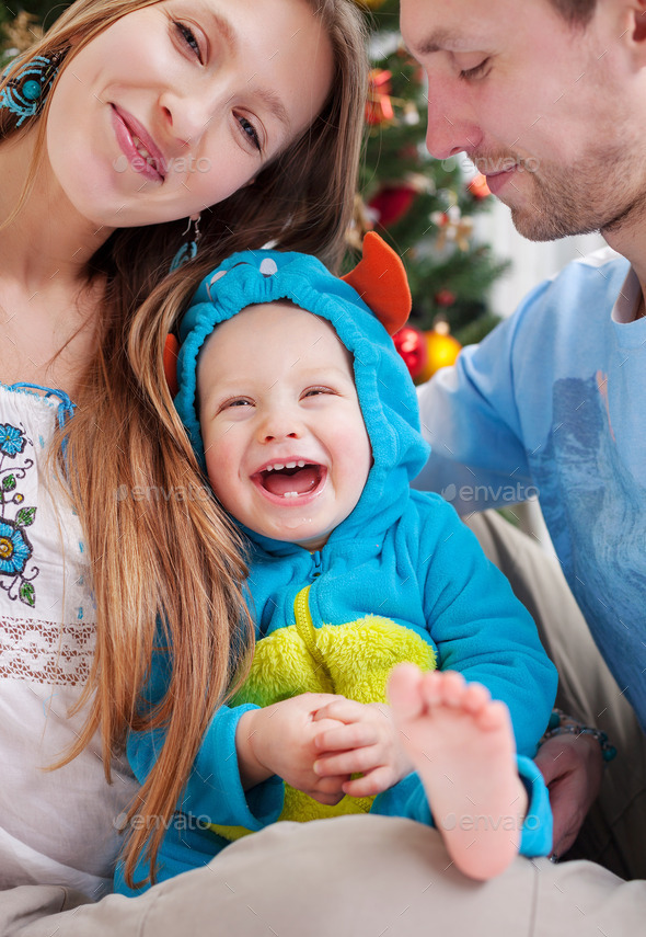 Happy parents with baby son dressed in little monster costume at Christmas time