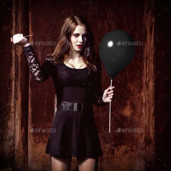 Weird angry girl is piercing a black balloon by needle (Misc) Photo Download