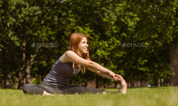 Pretty redhead smiling stretching in park on a sunny day (Misc) Photo Download