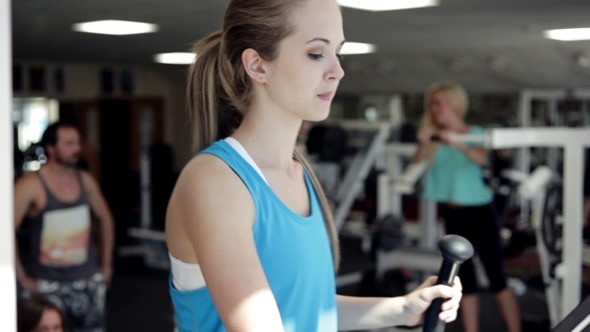 Young Woman Uses Elliptical Cross in a Gym Young Woman Uses Elliptical Cross in a Gym