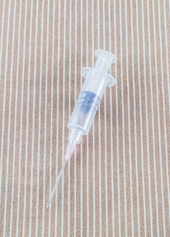 Syringe with needle on brown cloth background