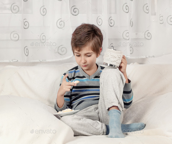 Boy drinking tea and eating biscuits. Toned image. (Misc) Photo Download