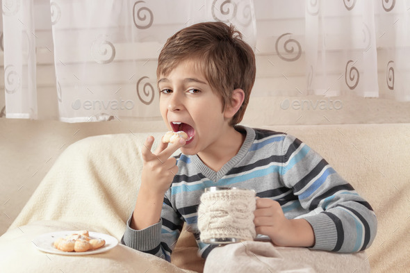 Boy drinking tea and eating biscuits. Toned image. (Misc) Photo Download