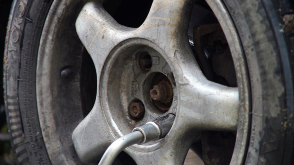 Man Turning Off Screws From Car Rear Wheel Man Turning Off Screws From Car Rear Wheel