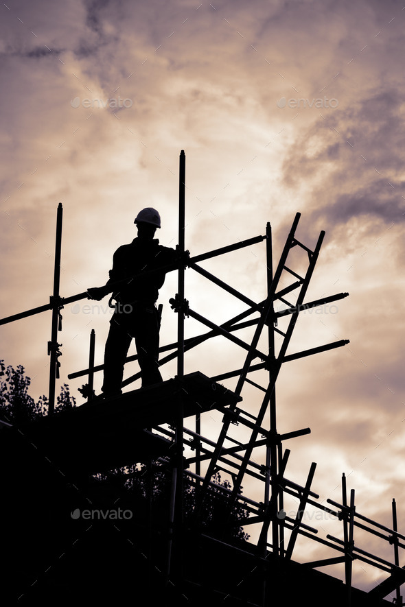 builder on scaffolding building site at sunset