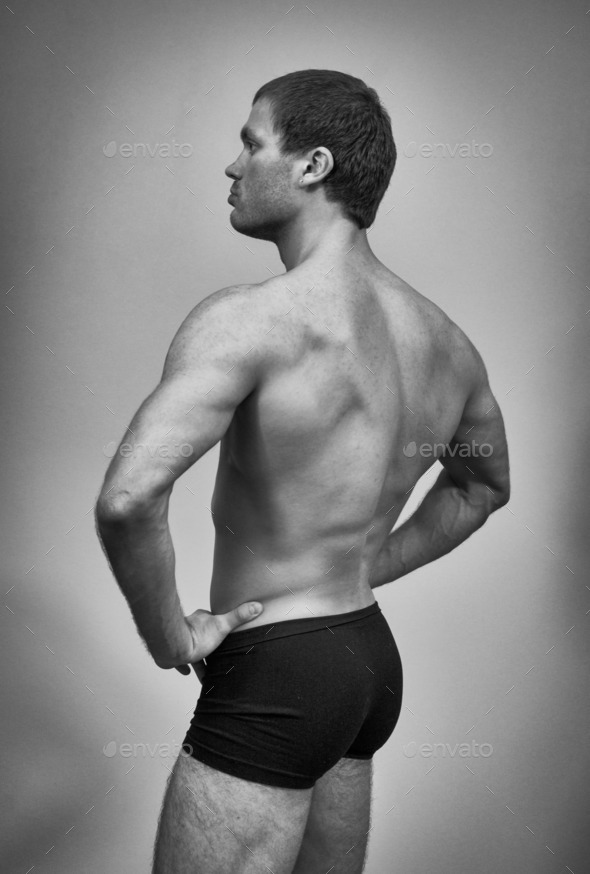 Muscular male model posing. Back view. Black and white.