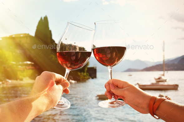 Two wineglasses in the hands. Varenna town at the lake Como, Ita (Misc) Photo Download