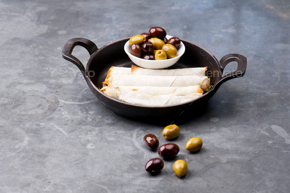 Cheese rolls plate with olives served in a black pan
