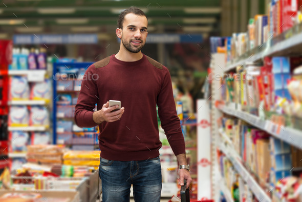 Man Looking At Mobile Phone In Shopping Centre