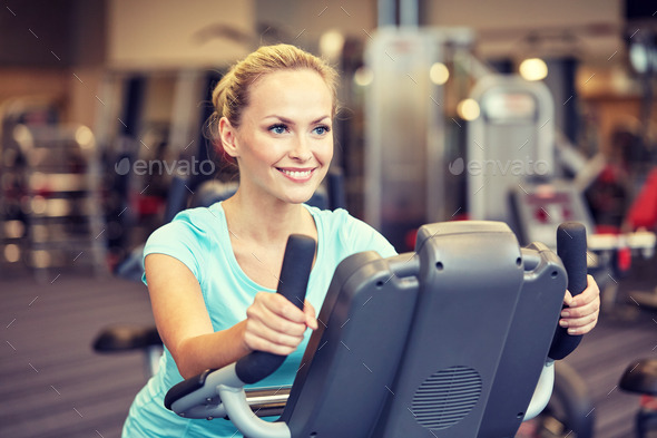 smiling woman exercising on exercise bike in gym (Misc) Photo Download