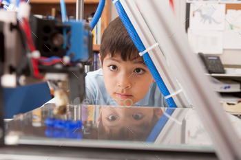Boy watches 3d printer.