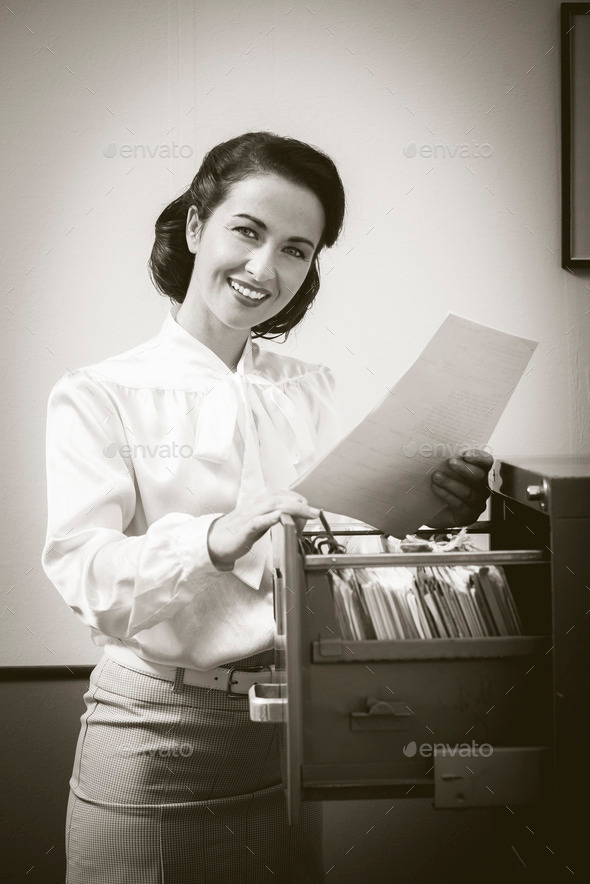 Smiling secretary searching files in the filing cabinet