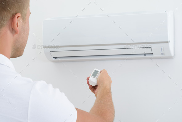 Man Holding Remote Controller Of Air Conditioner