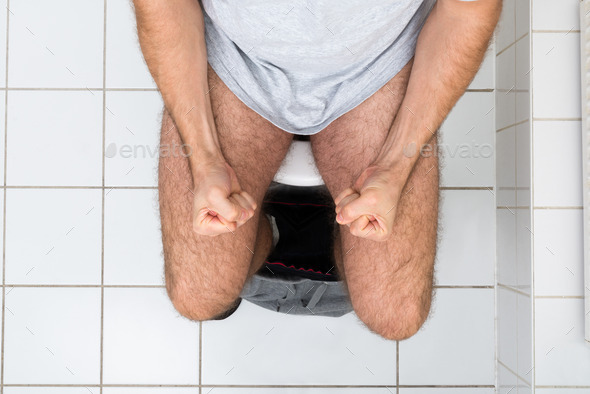 Man Clenching His Fist Sitting On Toilet Bowl