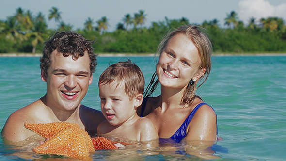 Parents And Son In Sea Water Holding Starfish Parents And Son In Sea Water Holding Starfish