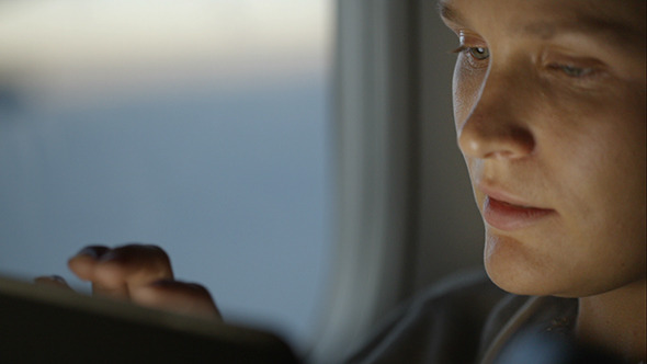 Woman Using Pad During Flight And Looking Out Woman Using Pad During Flight And Looking Out