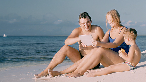 VideoHive Happy Family Of Three Sitting By The Sea And Using 10150884 VideoHive Happy Family Of Three Sitting By The Sea And Using 10150884
