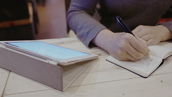 Woman Taking Notes In Notebook Touch Pad Nearby Woman Taking Notes In Notebook Touch Pad Nearby