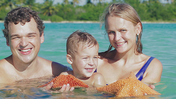Parents And Son In Sea Water Holding Starfish Parents And Son In Sea Water Holding Starfish