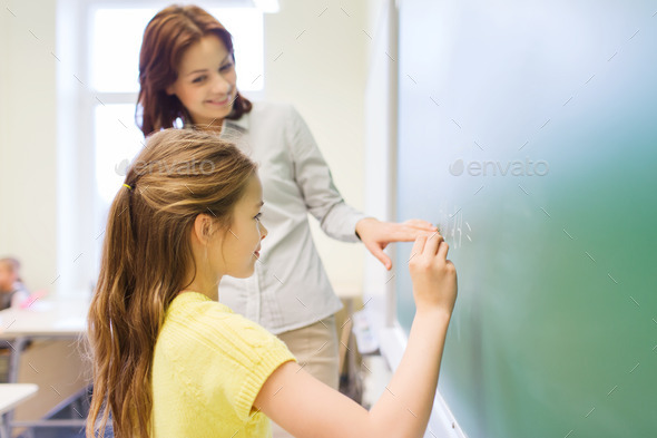little smiling schoolgirl writing on chalk board (Misc) Photo Download