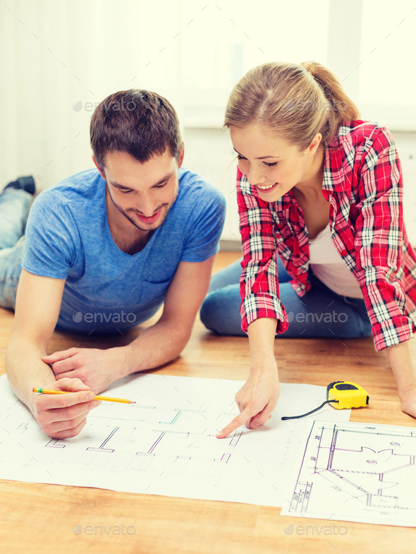 smiling couple looking at blueprint at home (Misc) Photo Download