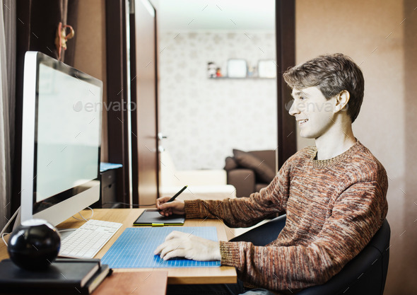 Young man at home using a computer, freelance developer or desig