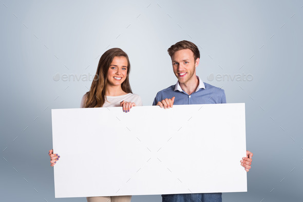 Happy young couple with blank board against grey vignette (Misc) Photo Download