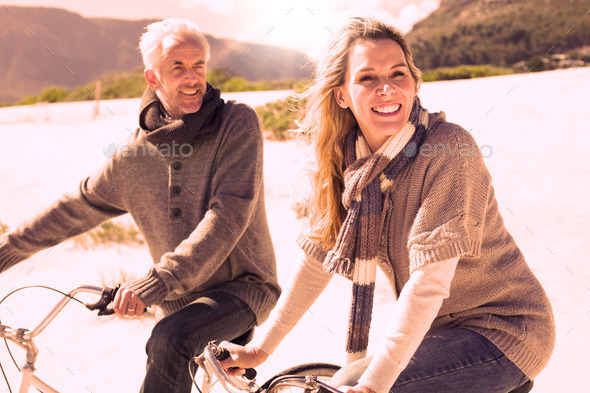 Carefree couple going on a bike ride on the beach on a bright but cool day (Misc) Photo Download