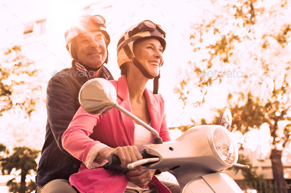 Happy senior couple riding a moped on a sunny day (Misc) Photo Download