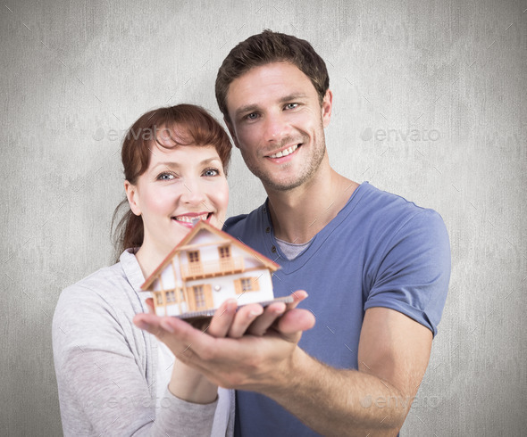 Couple holding a model house against weathered surface (Misc) Photo Download