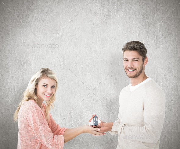 Attractive couple holding miniature house model against white background (Misc) Photo Download