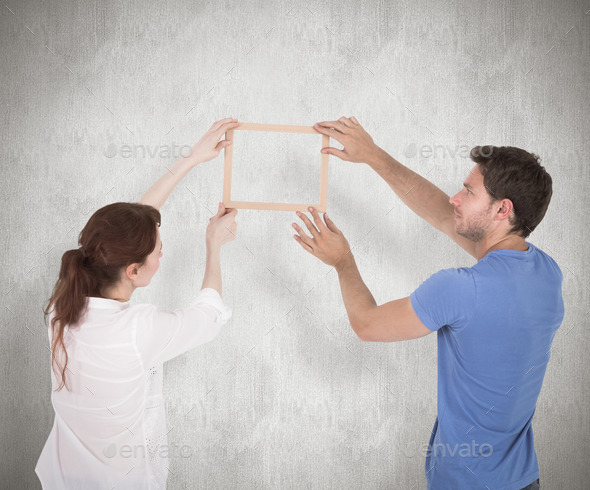 Couple deciding to hang picture against weathered surface (Misc) Photo Download