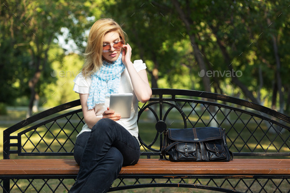 Young fashion woman using tablet computer in a city park