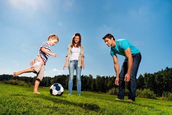 Happy young family playing football outdoors (Misc) Photo Download