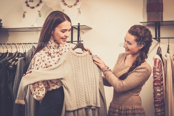 Young woman choosing clothes on a rack in a showroom (Misc) Photo Download