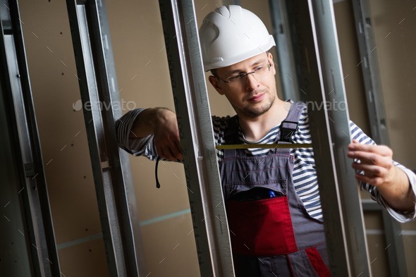 Builder measuring distance with tape during construction (Misc) Photo Download