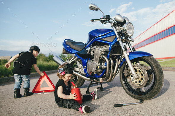 little biker repairs motorcycle on road (Misc) Photo Download
