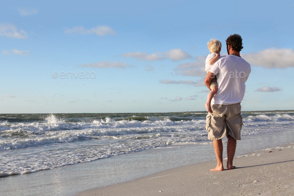 Young Child Resting in Father27;s Arms on Beach by Ocean