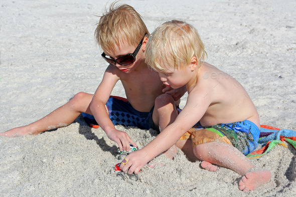 Two Young Children Playing Toys in the Sand at the Beach