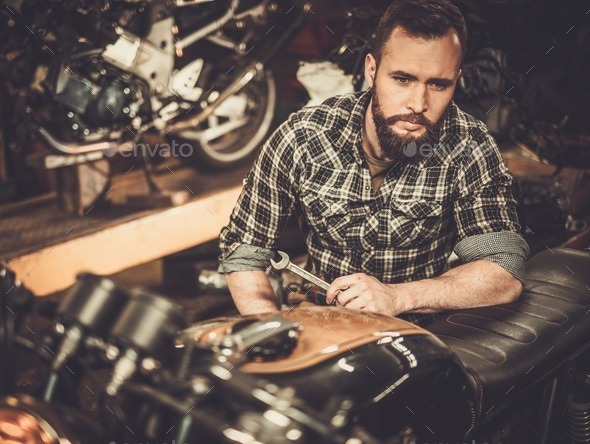 Mechanic building vintage style cafe-racer motorcycle in custom garage (Misc) Photo Download