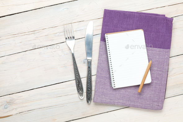 Notepad over kitchen towel and silverware on wooden table