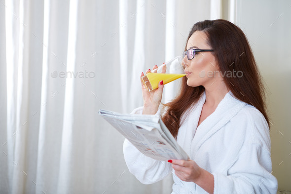 Woman reading the news while drinking orange juice (Misc) Photo Download