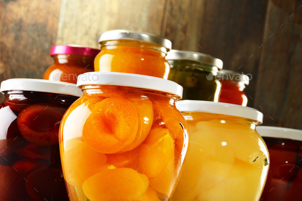 Jars with pickled vegetables, fruity compotes and jams isolated