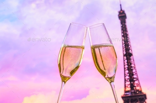 a pair of champagne flutes with golden bubbles on blur tower Eiffel background