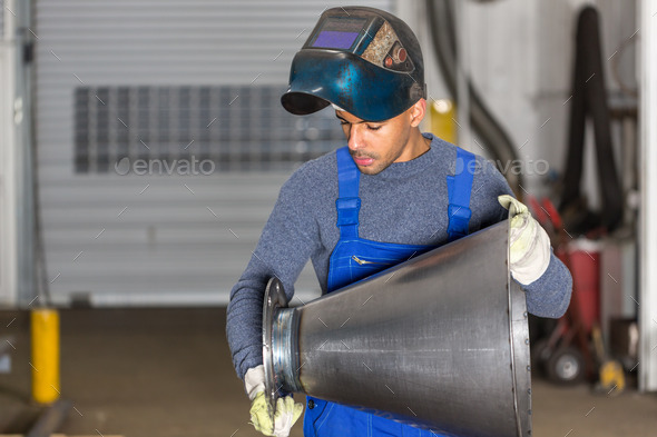Welder inspecting metal piece for quality control