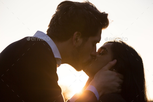 Couple in love kissing in front of sunset